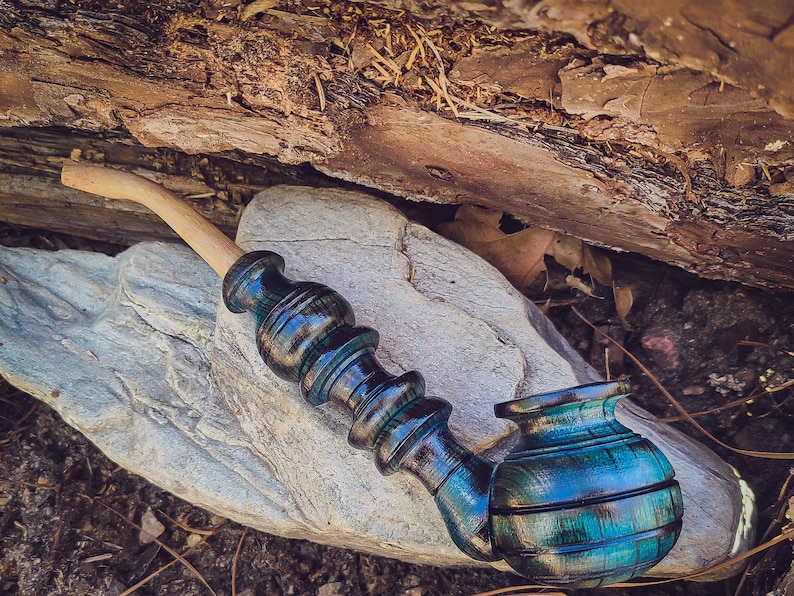 May include: A wooden smoking pipe with a dark blue and green stain finish. The pipe has a long, curved stem and a round bowl.