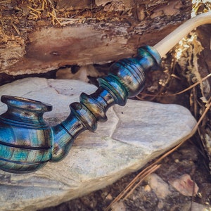 May include: A wooden smoking pipe with a blue, green, and black swirl pattern. The pipe has a long, curved stem and a bowl with a rounded shape.