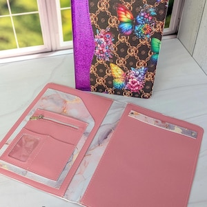 May include: A pink notebook cover with a butterfly and floral design. The cover features a brown background with gold chain links and colorful butterflies. The interior is pink with pockets and a zipper. The text "Daydream" and "NOTEBOOK COVER PDF PATTERN" are visible.