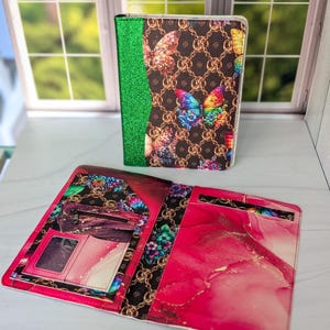 May include: A closed and an open wallet. The closed wallet has a brown butterfly pattern with a green glitter spine. The open wallet has a pink and white design with a zipper pocket and card slots.