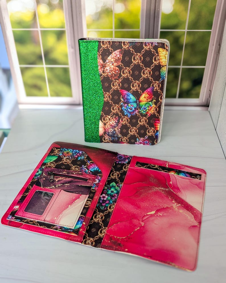 May include: A closed and an open wallet. The closed wallet has a brown butterfly pattern with a green glitter spine. The open wallet has a pink and white design with a zipper pocket and card slots.