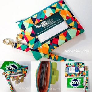 Puede incluir: Una bolsa de cremallera turquesa con un patr&oacute;n geom&eacute;trico en tonos de naranja, rojo, verde y azul. La bolsa tiene una ventana de pl&aacute;stico transparente para mostrar una tarjeta de identificaci&oacute;n. La bolsa est&aacute; unida a una correa turquesa y blanca con un llavero dorado. El texto "ESSEX COUNTY LIBRARY www.essexcountylibrary.ca This card can be used at all Branches of the Essex County Library" est&aacute; impreso en la ventana de la tarjeta de identificaci&oacute;n. El texto "Made Sew Well" est&aacute; impreso debajo de la bolsa.