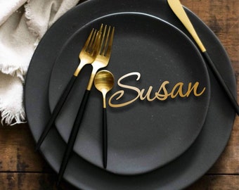 May include: Black and gold place setting with a gold name card that reads "Susan".