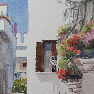 Puede incluir: Pintura acuarela de un edificio blanco con una ventana y un balc&oacute;n con flores rojas. Un gato blanco y negro se sienta en el alf&eacute;izar de la ventana.