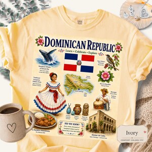 May include: A pale yellow t-shirt featuring a graphic print of the Dominican Republic. The design includes the national flag, a map, a person in a traditional dress, a drummer, a plate of food, a historic building, and various cultural icons.
