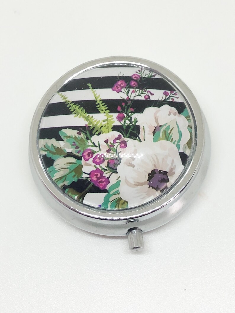 Pill box with a flowered image on black and white lines glass dome