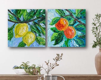May include: Two paintings of fruit on branches. The left painting shows two yellow lemons on a branch with green leaves against a blue sky. The right painting shows two orange-red fruits on a branch with green leaves against a blue sky.