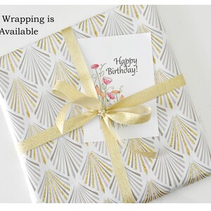 May include: A white gift box with a gold and gray geometric pattern. The box is wrapped with a gold ribbon and a white card that says "Happy Birthday!"