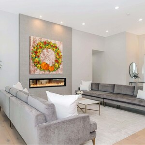 May include: A modern living room with a gray sectional sofa, a fireplace, and a large wall art piece featuring a wreath of fall leaves and pumpkins.