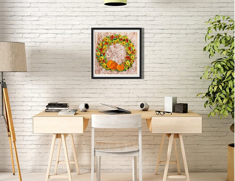 May include: A framed print of a fall-themed wreath with orange pumpkins and yellow flowers on a white brick wall background.