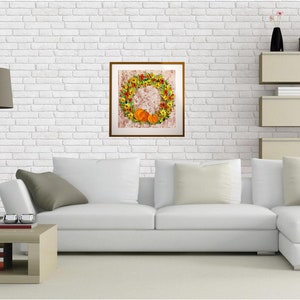 May include: A white couch with gray pillows in a living room setting. A framed picture of a fall wreath with pumpkins hangs on a white brick wall.