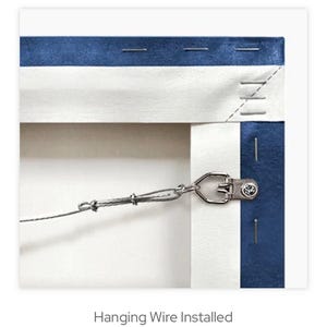 May include: Detail of the back of a canvas artwork, with blue and white fabric edges. A metal hanging bracket and wire are fitted for display. The text "Hanging Wire Installed" is visible at the bottom.