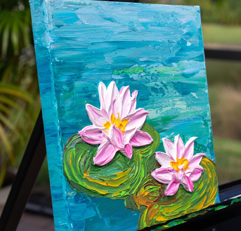 May include: A painting of two pink water lilies with yellow centers on a blue and green background. The lilies are painted in a textured style, giving the impression of brushstrokes.