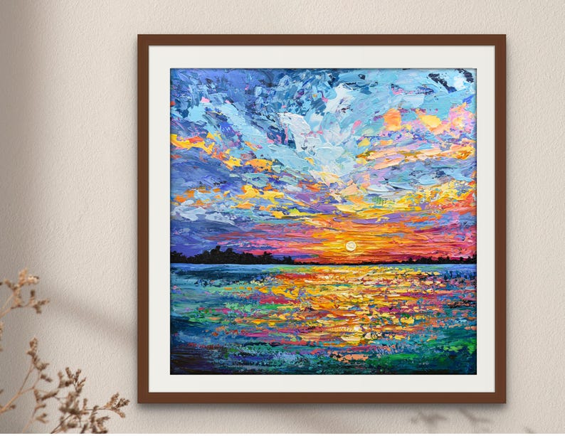 May include: A framed abstract painting of a sunset over water. The sky is a mix of blues, yellows, and oranges, with textured brushstrokes. The water reflects the colors of the sky, with a dark horizon line.