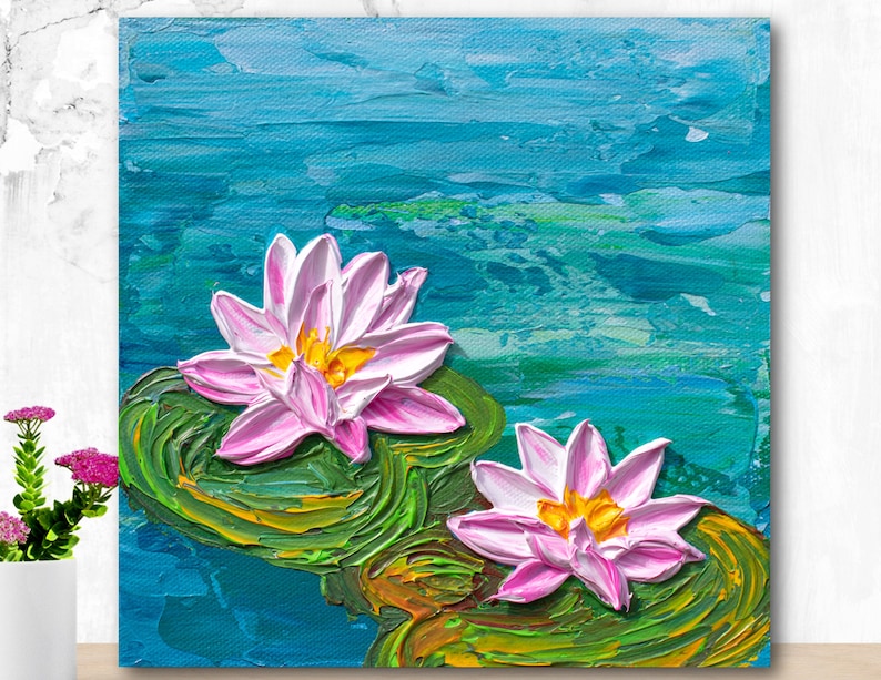 May include: A painting of two pink water lilies with yellow centers on green lily pads. The lilies are floating on a blue and green water background.