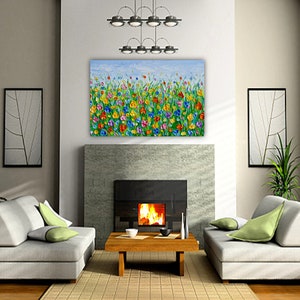 Puede incluir: Una vibrante pintura floral con un cielo azul de fondo cuelga sobre una chimenea. La obra de arte presenta flores coloridas en tonos de rojo, amarillo, azul y verde. La habitaci&oacute;n incluye dos sof&aacute;s grises, una mesa de centro de madera y plantas decorativas.
