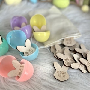 K&ouml;nnte beinhalten: Ein Set aus pastellfarbenen Plastik-Ostereiern mit Hasen-f&ouml;rmigen Holz-Spielsteinen im Inneren. Die Spielsteine haben verschiedene Spr&uuml;che darauf geschrieben, wie "Spielen", "Fahrrad fahren", "S&uuml;&szlig;es machen" und "Pizza-Abend".