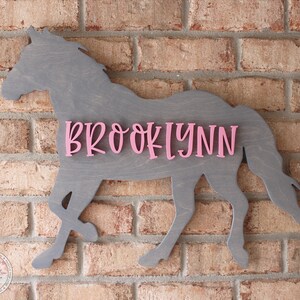 May include: A gray wooden horse silhouette with the name "BROOKLYNN" in pink letters.