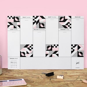 May include: A black and white geometric weekly planner with pink accents. The planner has a grid layout with spaces for each day of the week, including Monday, Tuesday, Wednesday, Thursday, Friday, and weekend. The planner also includes a section for notes and a section for a monthly calendar.