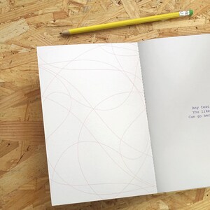 May include: An open notebook with a white cover and pink lines on the left page. The right page has the text "Any text you like can go here." printed in blue.