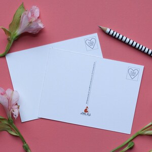 May include: Two blank white postcards with a red fox illustration and the text "Little Fox" on the bottom right corner. The postcards have a heart-shaped stamp with the text "Place Stamp Here" on the top left corner. The postcards are on a pink surface with pink flowers.