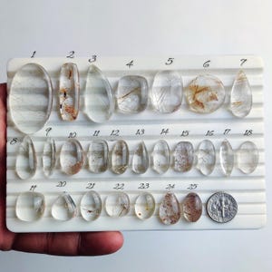 May include: A set of three ceramic mugs with a speckled, matte finish. The mugs are in shades of cream, light gray, and dark gray. Each mug has a simple, minimalist design and a rounded handle.