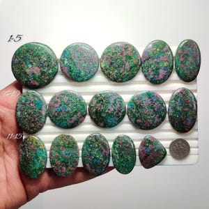 Puede incluir: Una colección de piedras preciosas pulidas en varias formas, incluyendo redondas y ovaladas. Las piedras muestran una mezcla de tonos verdes, rosas y azules, con un patrón moteado. La imagen incluye el texto "1-5", "6-10" y "11-15".