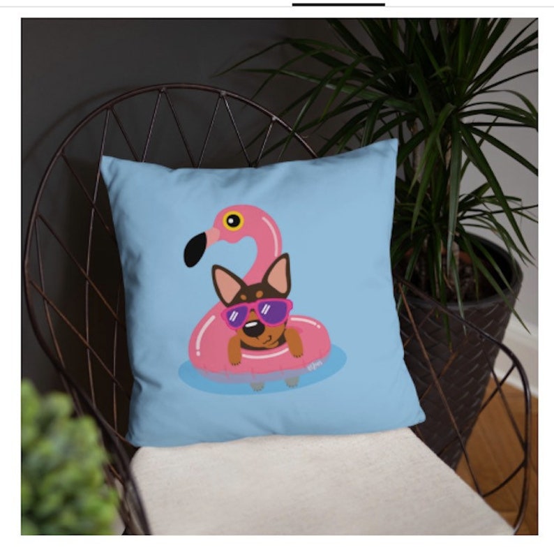 May include: A blue throw pillow with a cartoon illustration of a dog wearing sunglasses and floating on a pink flamingo pool float.