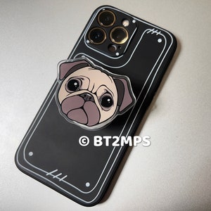 May include: Black phone case with a clear plastic pug phone grip. The phone case has a camera bump with three lenses. The phone grip has a white outline and the text "BT2MPS" is printed on the case.