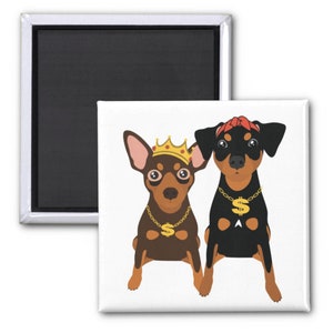 Op de afbeelding: Twee dwergpinchers met gouden kettingen en bedels. De ene hond draagt een gouden kroon en de andere een rode bandana.