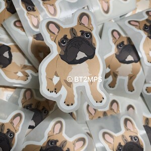 May include: A stack of stickers featuring a cartoon French Bulldog with brown fur, black eyes, and pink ears. The sticker has a white outline and the text "&copy;BT2MPS" in the bottom centre.