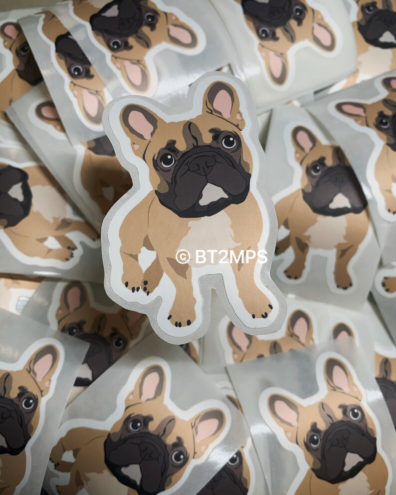 May include: A stack of stickers featuring a cartoon French Bulldog with brown fur, black eyes, and pink ears. The sticker has a white outline and the text "&copy;BT2MPS" in the bottom centre.