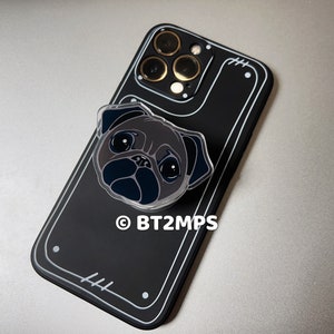 May include: Black phone case with a clear plastic pug phone grip. The phone case has a black camera bump with gold accents. The text "BT2MPS" is printed on the case.