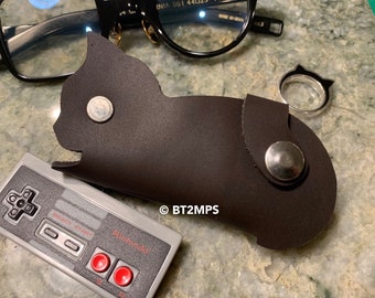 May include: A brown leather cat-shaped key chain with a silver snap closure. The keychain has the text "© BT2MPS" printed on it.
