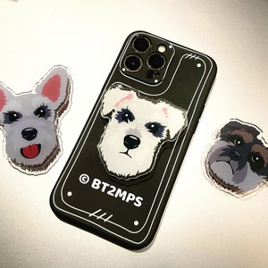 Op de afbeelding: Een zwarte iPhone-hoes met een witte hondensticker op de achterkant. De hoes heeft een witte omtrek en de tekst "BT2MPS" in wit. Er zijn twee andere witte hondenstickers op een witte achtergrond.