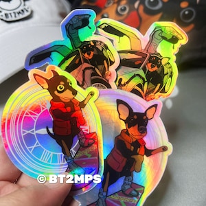 May include: Three iridescent holographic stickers featuring a cartoon dog wearing a red vest and riding a hoverboard. The stickers are set against a white background. The text "BT2MPS" is visible on one of the stickers.