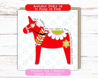 May include: A square greeting card featuring a red Dala horse illustration with green and white floral patterns, a pink saddle, and text reading Dala horse, With Love, Grace & Magic for the festive season & beyond, Available Singly or in Packs of Five!