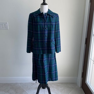 May include: A green and blue plaid skirt suit with a button-up jacket and a matching skirt.