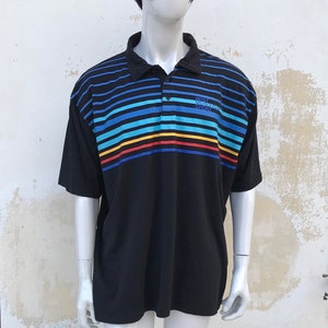 May include: Black short-sleeved polo shirt with horizontal stripes in blue, yellow, red, and white. The shirt has a button-up collar and the text "BEST 1978-2005 SPORT" printed on the right side of the chest.