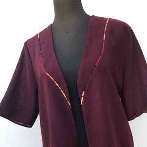 Vinröd 80-tals vintagekavaj utan knappar, med färgglada detaljer, tillverkad i Grekland