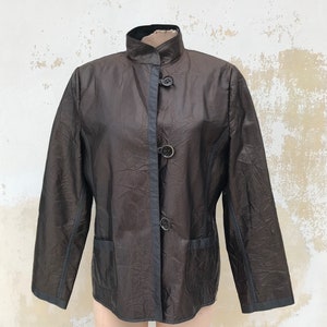 May include: A black and brown striped jacket with a mandarin collar and three buttons. The jacket has a slightly textured fabric and a slim fit.