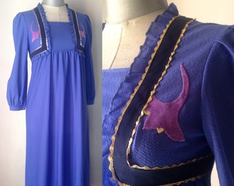 La robe de chat parfaite a été fabriquée en Grèce dans les années 1970 ! Encolure carrée, manches bouffantes, passepoil doré et magnifique coloration bleu/violet