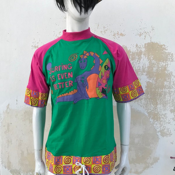 Dinosaurs surfing, crazy kitschy, vibrant colored late 80s/early 90s men’s T-shirt features mao collars and drawstring finishing