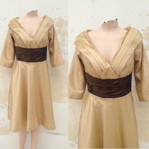 May include: A gold satin dress with a brown satin sash. The dress has a V-neckline and three-quarter sleeves.