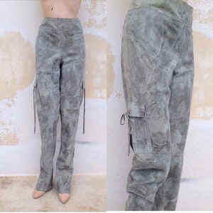 Peut inclure: Pantalon cargo en daim gris avec une taille haute et un détail de laçage sur le côté. Le pantalon a un aspect vieilli et est fait d'un matériau doux et confortable.