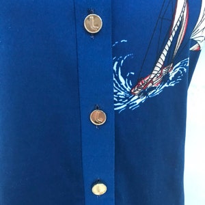 May include: A blue button-down shirt with a sailboat print and gold buttons.