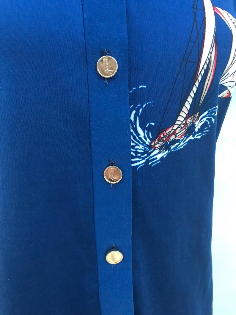 May include: A blue button-down shirt with a sailboat print and gold buttons.