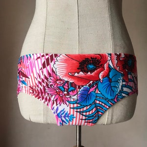 May include: Floral print underwear with pink, red, blue, and white flowers on a white background.