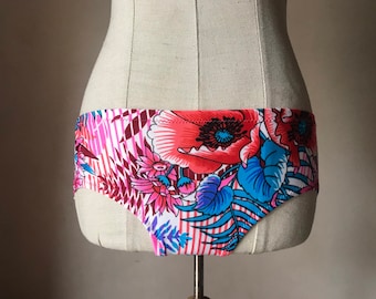 Pode incluir: Calcinha de estampa floral com flores rosa, vermelhas, azuis e brancas sobre fundo branco.