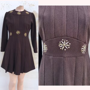 Schokobraunes 70er Jahre Vintage Minikleid in A-Linie mit Plisseedesign vorne und am Rock. Gesticktes Blumenmuster am Ausschnitt und in der Taille